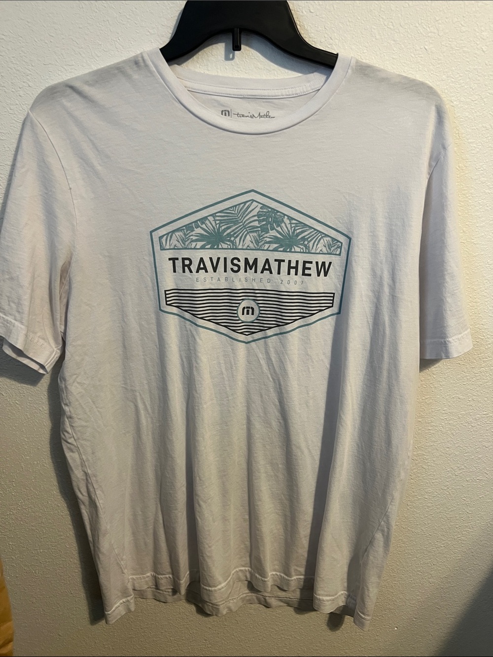 Travis Mathew White Tee with Teal Graphic Emblem